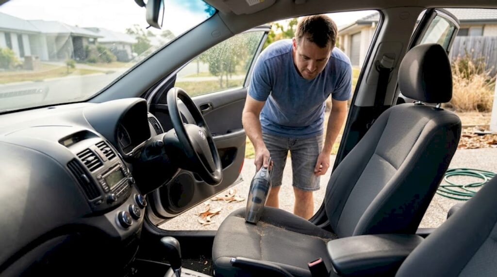 Man vacuuming car seat Sunshine Coast driveway