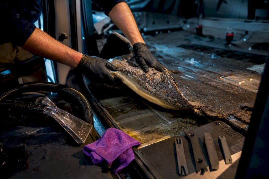 Technician exposing damp vehicle floor during teardown